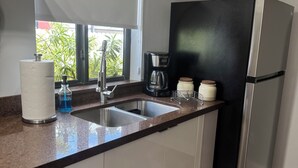 Et moderne køkken med en stålvask, et sort køleskab og en kaffemaskine.