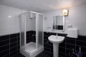 A bathroom with a glass-enclosed shower, a white sink, and a mirror above it. - Sultan Otel  (Mardin)
