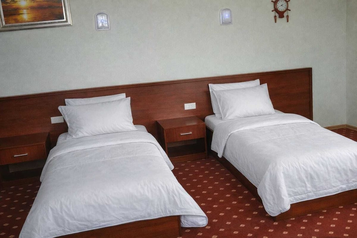Un lit double avec une tête de lit en bois, deux tables de chevet et un tapis à motifs.