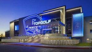 A modern building with a large illuminated sign reading "TOPGOLF".