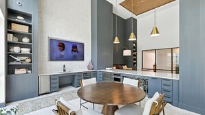 A modern kitchen with a round dining table, built-in shelves, and pendant lighting.