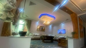 A modern living room with a large sofa, a coffee table, and a TV mounted on the wall.