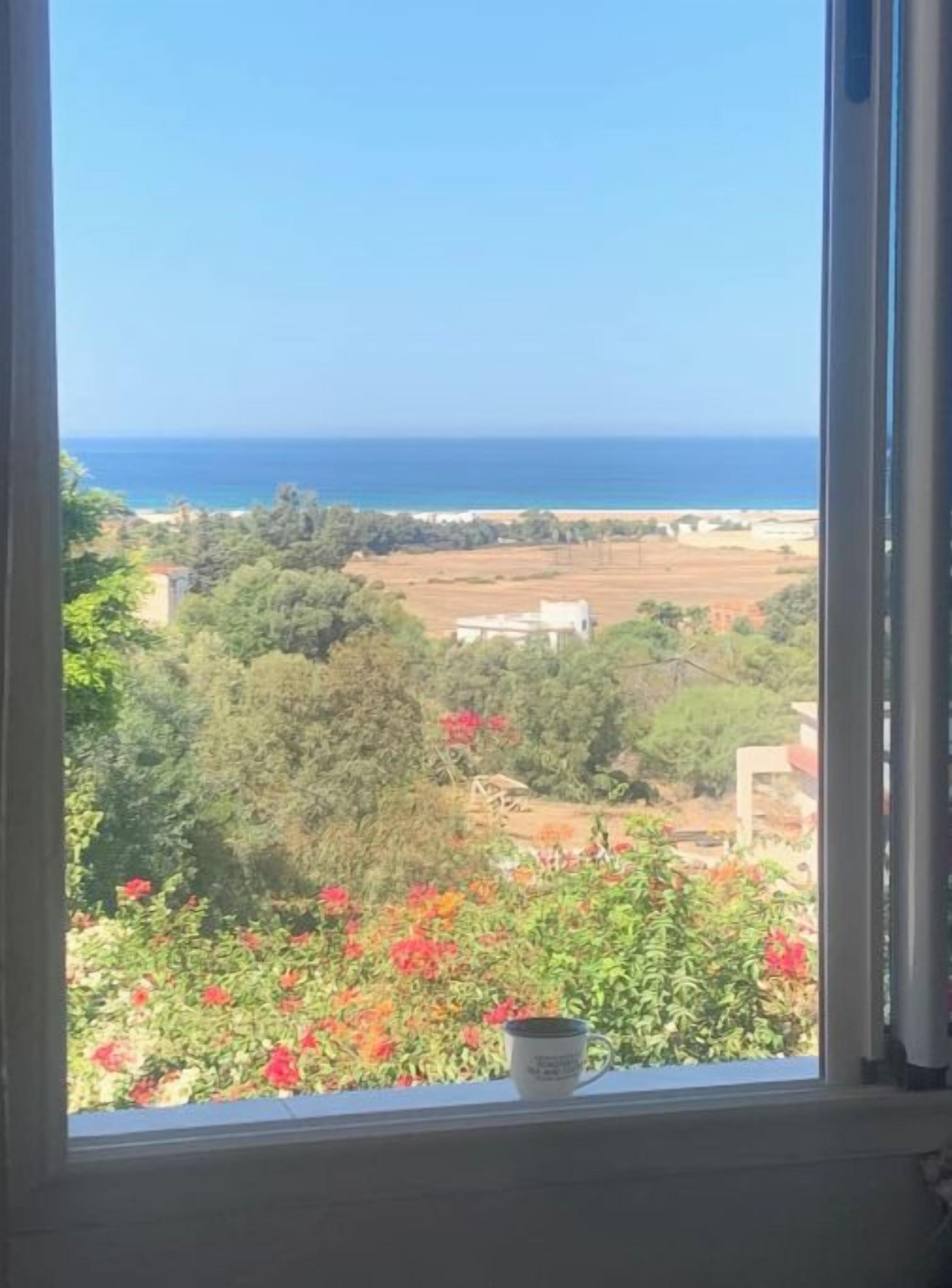 A view from a window overlooking a coastal landscape with a clear sky.