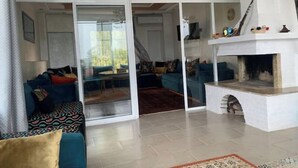 A spacious living room with a large glass door leading to a balcony, a fireplace, and a sofa set. - Spacious one-bedroom apartment close to the sea (Tanger)