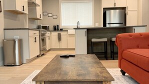 A modern kitchen with white cabinets, a stainless steel refrigerator, and a wooden dining table. - Walk to Silos 2BR 2.5BA Townhome + Chef Kitchen Greenville Clemson Area (Easley)