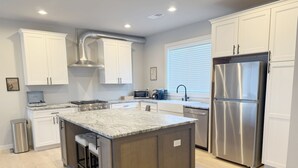 Una cocina moderna con gabinetes blancos, electrodomésticos de acero inoxidable y una isla central.
