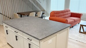 A modern kitchen with a granite countertop, white cabinetry, and a built-in island. - Walk to Silos 2BR 2.5BA Townhome + Chef Kitchen Greenville Clemson Area (Easley)