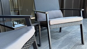 A modern outdoor seating area with wicker furniture and a glass partition. - Walk to Silos 2BR 2.5BA Townhome + Chef Kitchen Greenville Clemson Area (Easley)