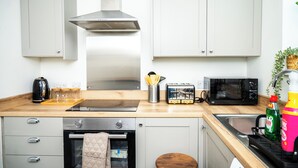 A kitchen with a microwave, toaster, kettle, and a sink.
