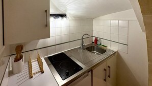 Eine Küche mit Spüle aus Edelstahl, Herd und weiß gefliestem Fliesenspiegel.
