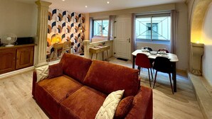 Ein Wohnzimmer mit einer Couch, einem Esstisch mit Stühlen, einer Küchenzeile und einem Fenster mit Blick.