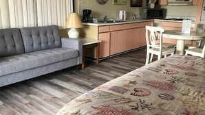 A room with a sofa, a dining table, a chair, a lamp, and a kitchen area. - Unit 222 Beautiful Cedar key (Cedar Key)