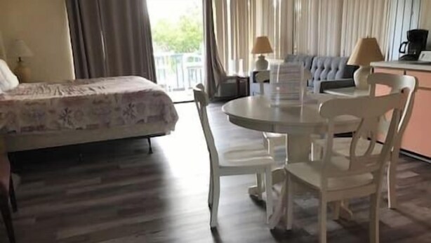 A hotel room with a bed, a round table with chairs, a sofa, and a view of the outdoors. - Unit 222 Beautiful Cedar key (Cedar Key)