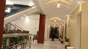 A spacious, well-lit hallway with a marble floor, a staircase on the left, and potted plants along the right wall. - Famous Gates Hotel Bomet  (Bomet)