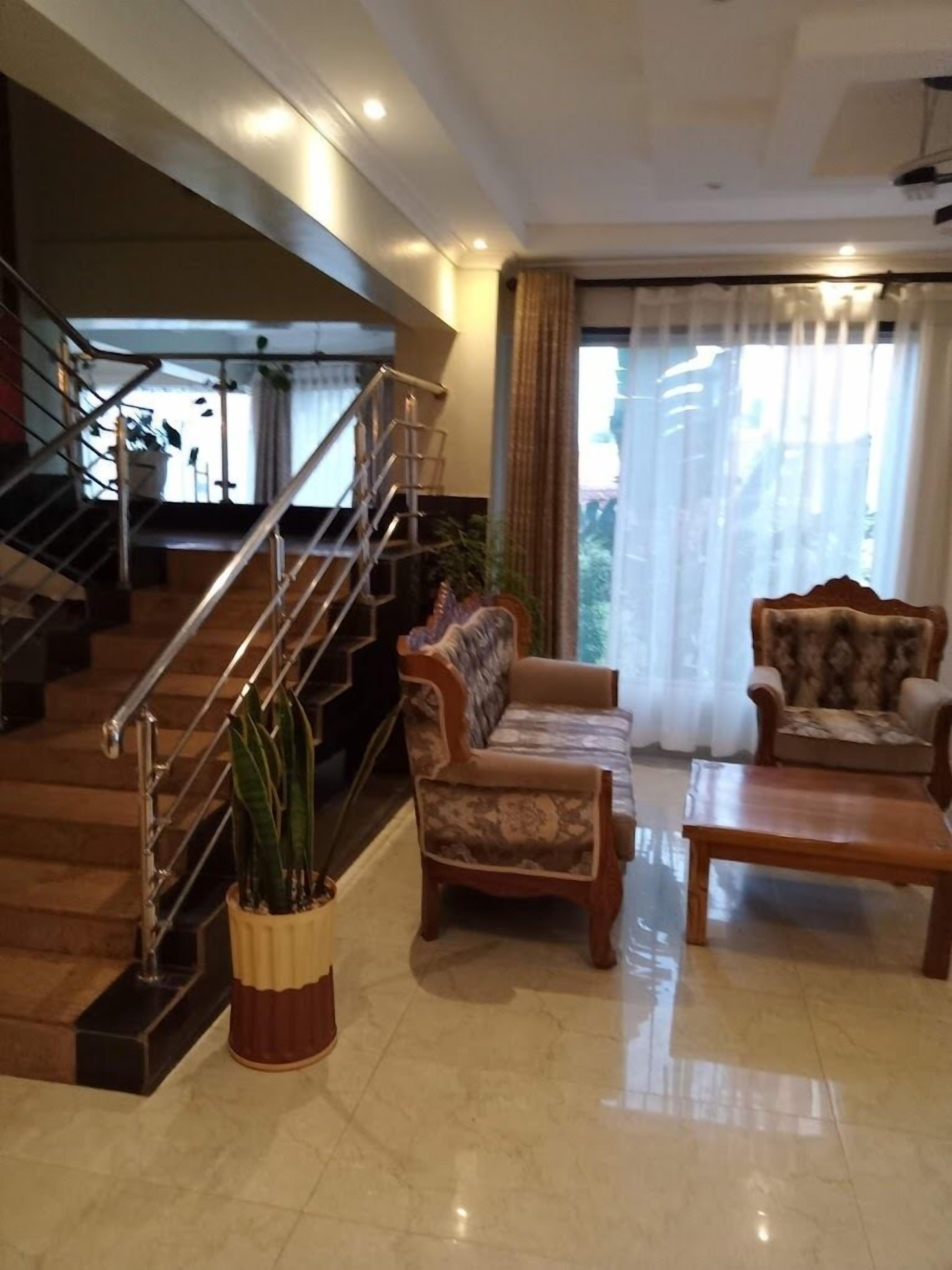 A spacious living area with a wooden staircase, a sofa, a chair, and a coffee table.