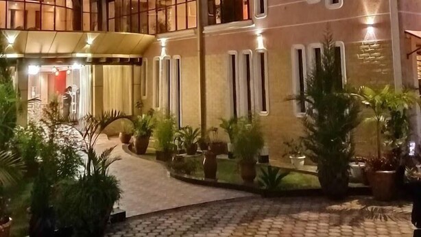 A multi-story hotel with a courtyard featuring potted plants and a tiled walkway. - Famous Gates Hotel Bomet  (Bomet)