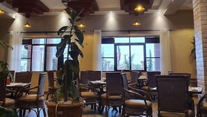 A spacious indoor area with wooden flooring, multiple tables and chairs, and large windows allowing natural light. - Famous Gates Hotel Bomet  (Bomet)
