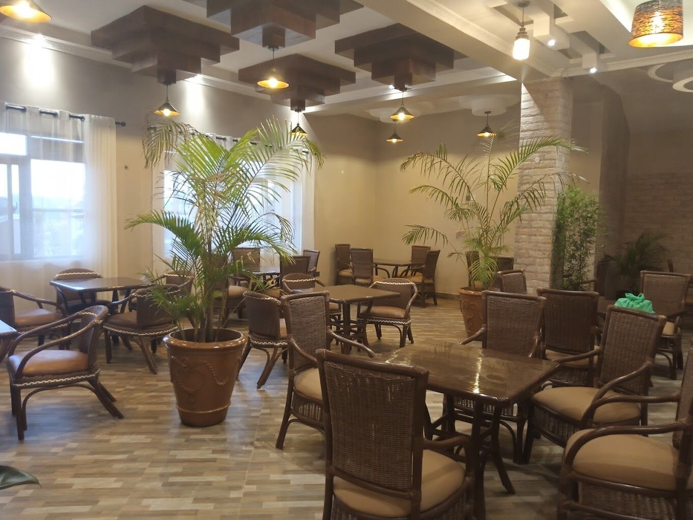 A spacious indoor area with high ceilings, wicker furniture, and potted plants.