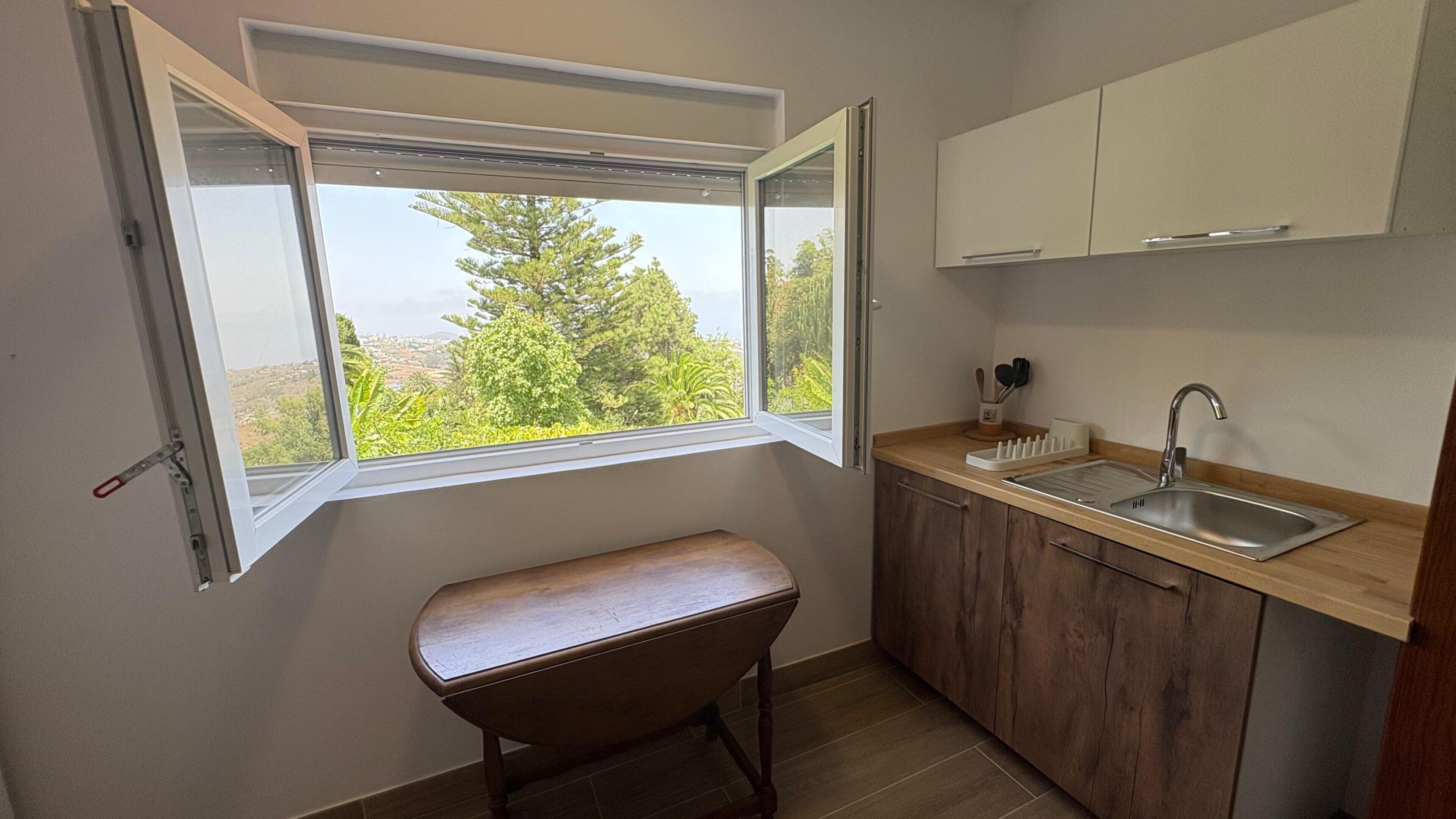 A small kitchen with a window, a bench, and a sink.