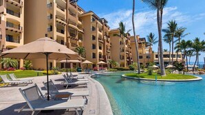Un resort con piscina, sillas de descanso y palmeras.