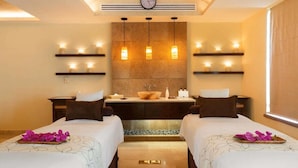 Habitación de hotel con dos camas, un espejo grande, un lavamanos y un reloj en la pared.