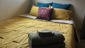 Een slaapkamer met een bed, kussens en een raam.