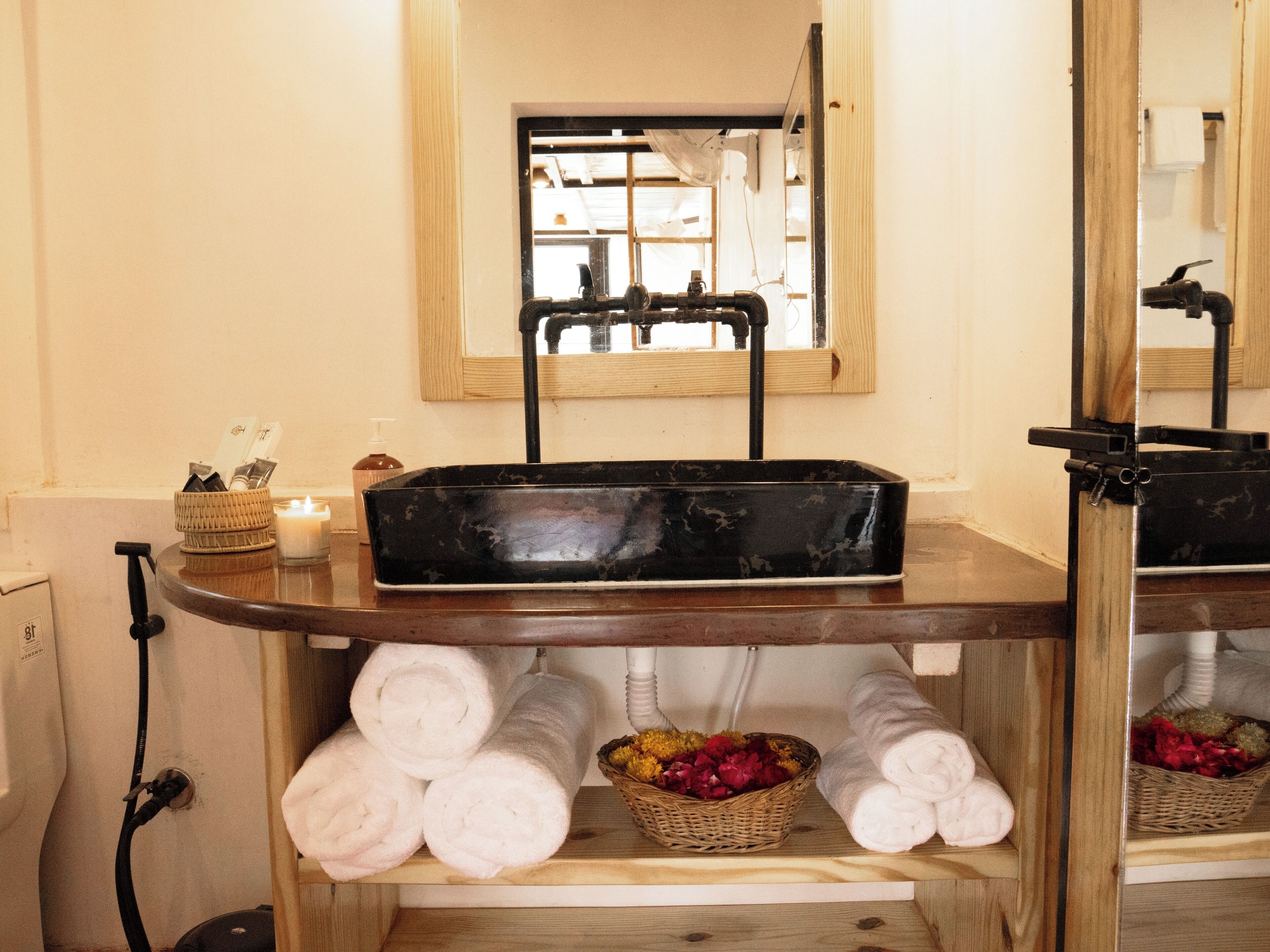 A bathroom with a wooden vanity, a black basin, and towels.