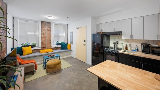 A compact kitchen with a built-in oven, a black refrigerator, and white cabinets. - Cozy 1BR Near Findlay Market and UC, Rhinegeist (Cincinnati)