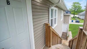 Une maison avec un escalier en bois menant à une porte d’entrée marquée d’un « B ».