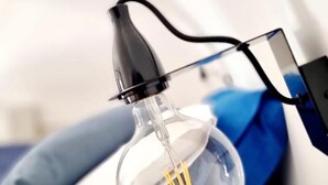 Gros plan d’une ampoule dont on peut voir le filament et le cordon électrique noir.