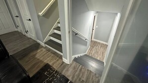Una escalera con barandilla, escalones de madera y una zona de descanso alfombrada.