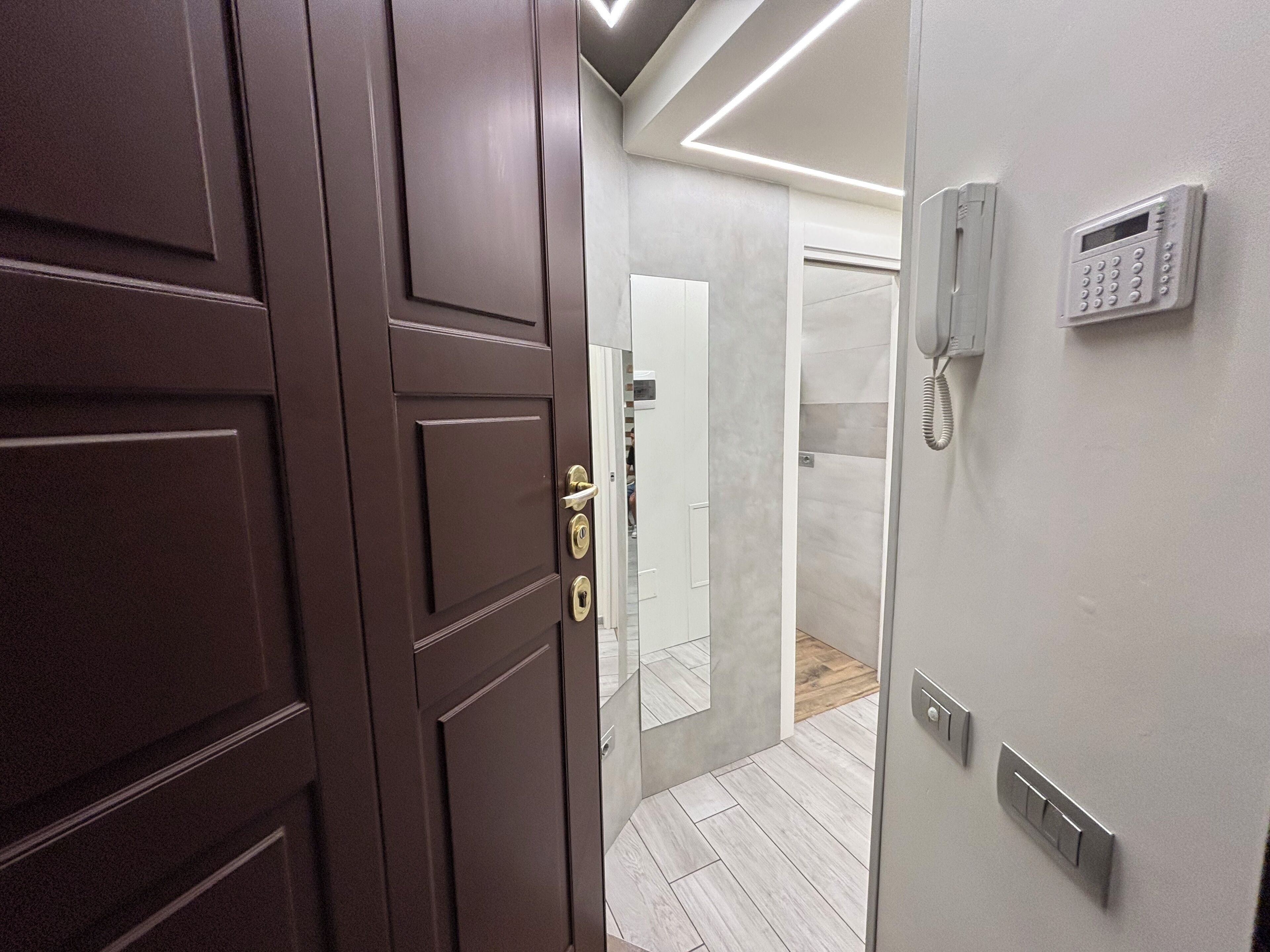Una habitación de hotel moderna con una puerta de madera, un teléfono y un interruptor de luz en la pared.