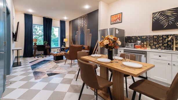 Una cocina moderna con comedor, con piso a cuadros, mesa de madera y sillas marrones.