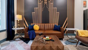 Una sala moderna con un sofá de cuero marrón, una mesa de centro con un adorno decorativo y una pared con diseños geométricos.
