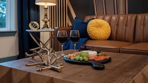 Una mesa de madera con una tabla de quesos, uvas y una botella de vino.