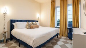 Siististi järjestetty hotellihuone, jossa on suuri sänky, yöpöytä ja työpöytä.