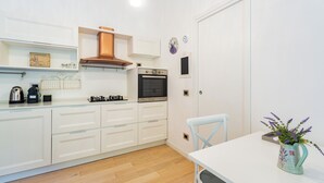 Een moderne keuken met witte kasten, een roestvrijstalen afzuigkap, een oven en een klein raam.