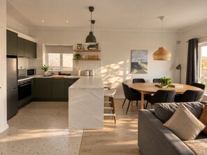 Une cuisine moderne avec un îlot central, un coin repas comprenant une table et des chaises en bois, et un canapé.