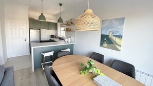 A modern kitchen with a central island, pendant lighting, and a dining area with a wooden table and chairs. - Stylish City Retreat - sleeps 6 (Galway)