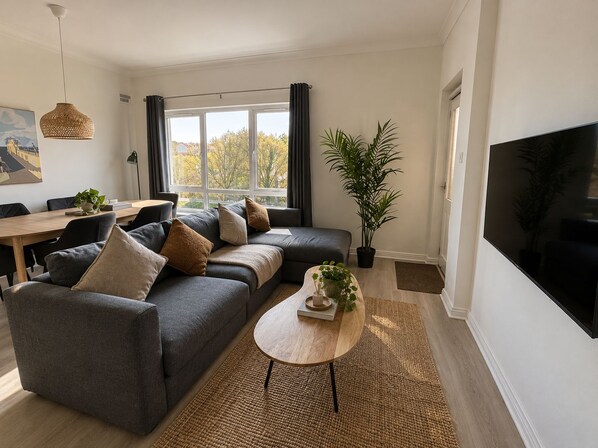 A modern living room with a sofa, coffee table, and a large TV.