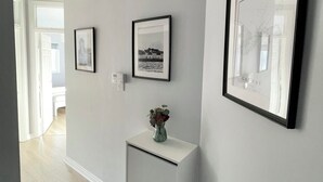 A hallway with a white console table, two framed pictures, and a vase with flowers. - Stylish City Retreat - sleeps 6 (Galway)