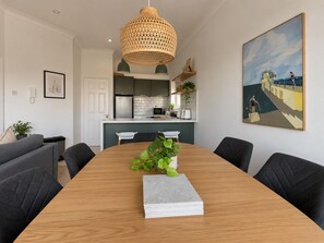 Une cuisine moderne avec des meubles de couleur sombre, un plan de travail blanc et un luminaire suspendu.