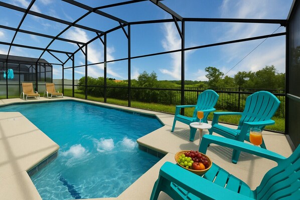 Ein Poolbereich mit Glasveranda, zwei türkisfarbenen Liegestühlen, einem Tisch mit Getränken und einer Obstschale.