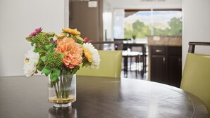 A dining table with a clear glass vase containing a bouquet of flowers.