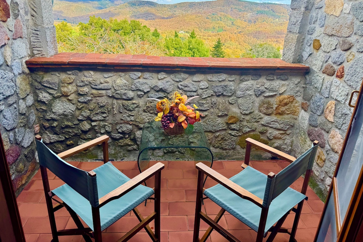 A stone-walled balcony with two wooden chairs and a wicker basket of autumn leaves.