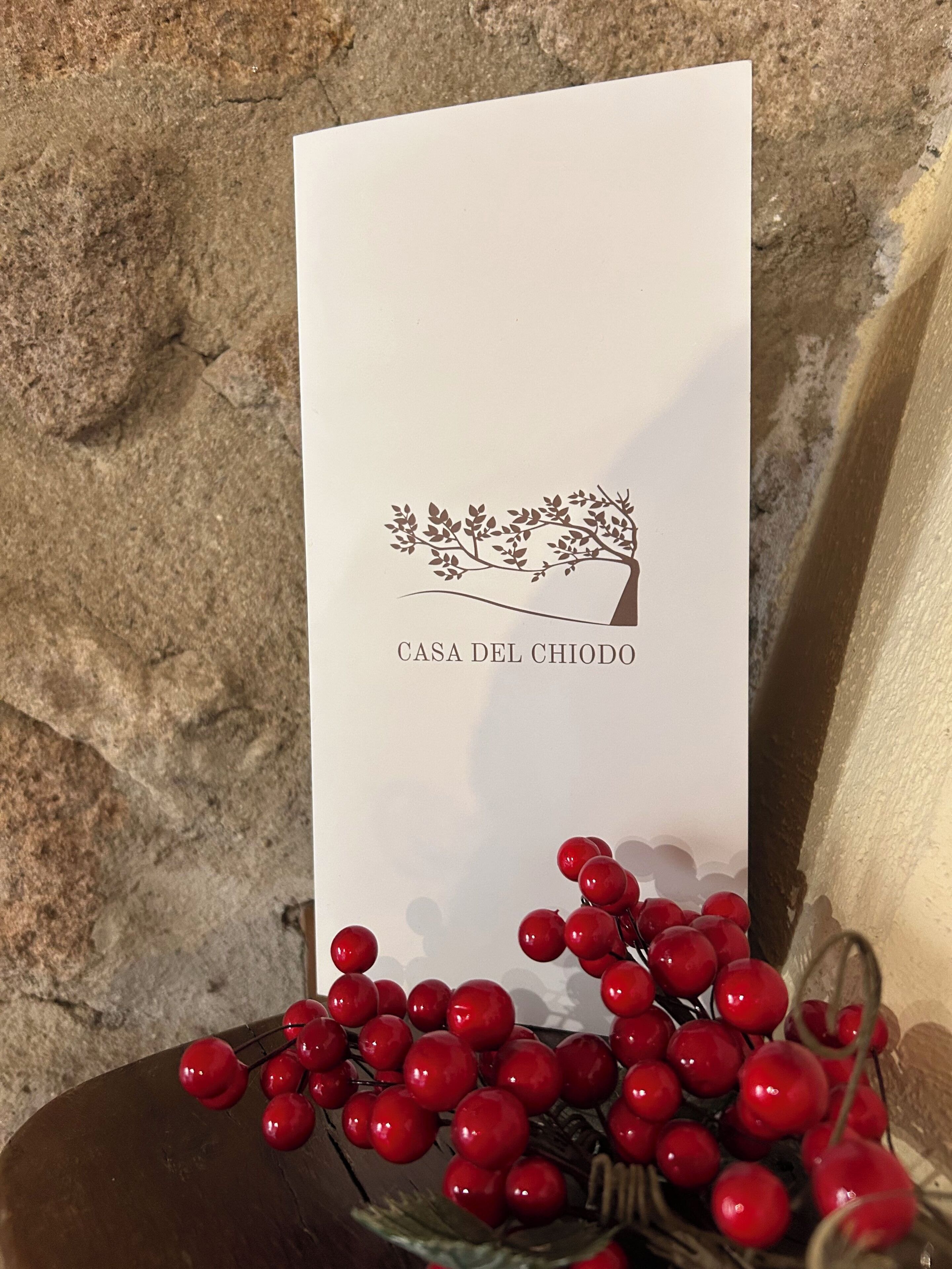 A sign with a tree and text 'CASA DEL CHIODO' against a stone wall background.