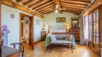 A rustic room with a wooden ceiling, a bed with floral bedding, a wooden dresser, and a window with curtains.