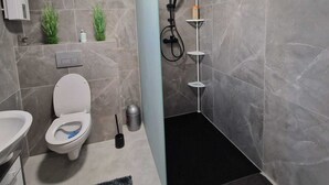 Une salle de bain moderne équipée de toilettes, d’un lavabo et d’une zone douche.