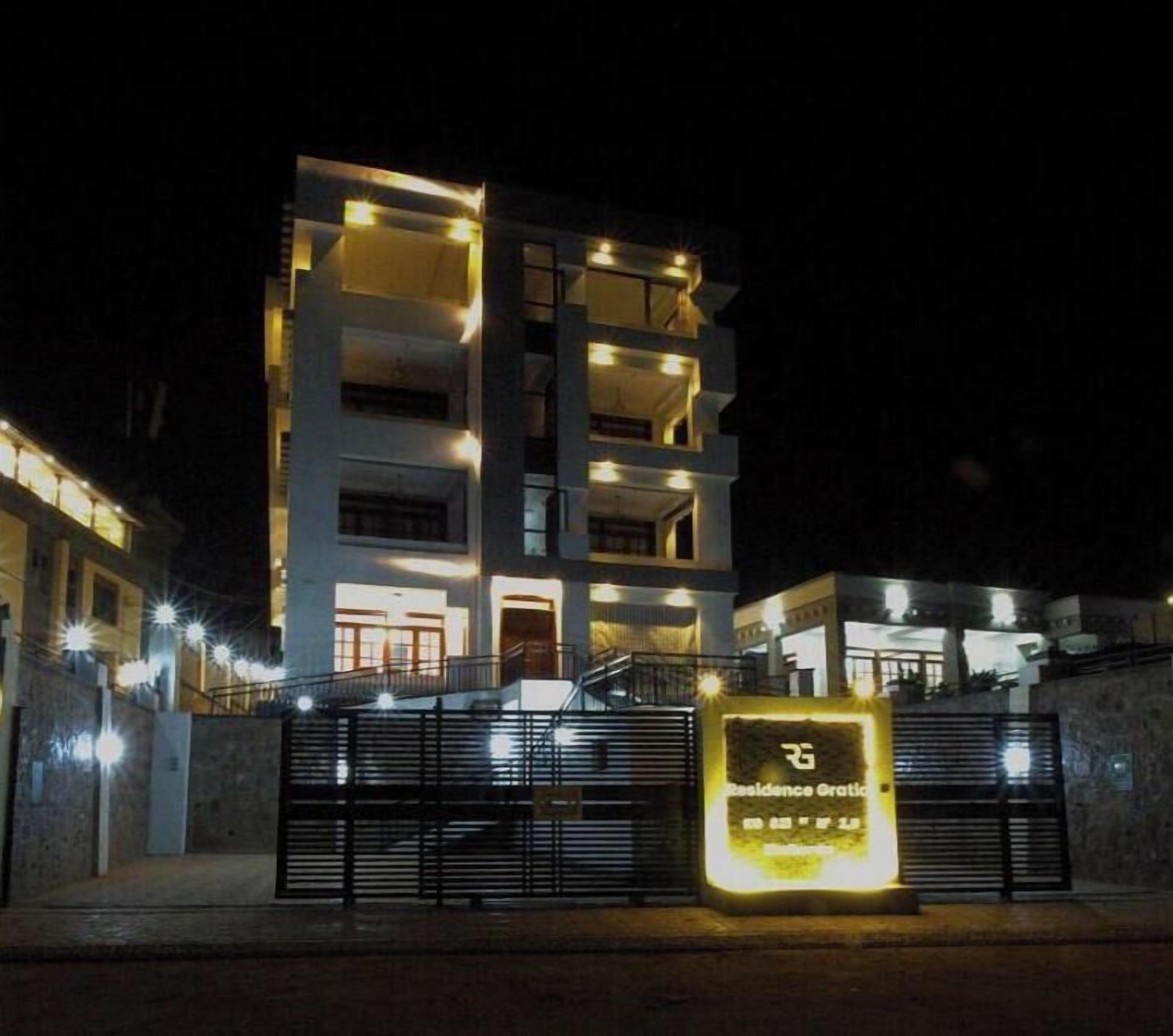 Un edificio de varios pisos con balcones y una entrada protegida por una reja.