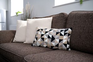 Ein braunes Sofa mit zwei Kissen, ein schlichtes und eines mit einem geometrischen Muster.
